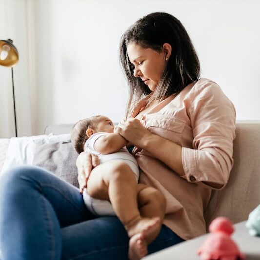 mom breastfeeding baby on couch